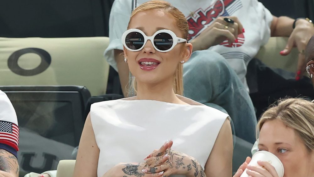 ariana-grande-embraces-1960s-styling-in-white-boatneck-dress-and-statement-sunglasses-at-2024-paris-olympics-with-cynthia-erivo-and-baz luhrmann